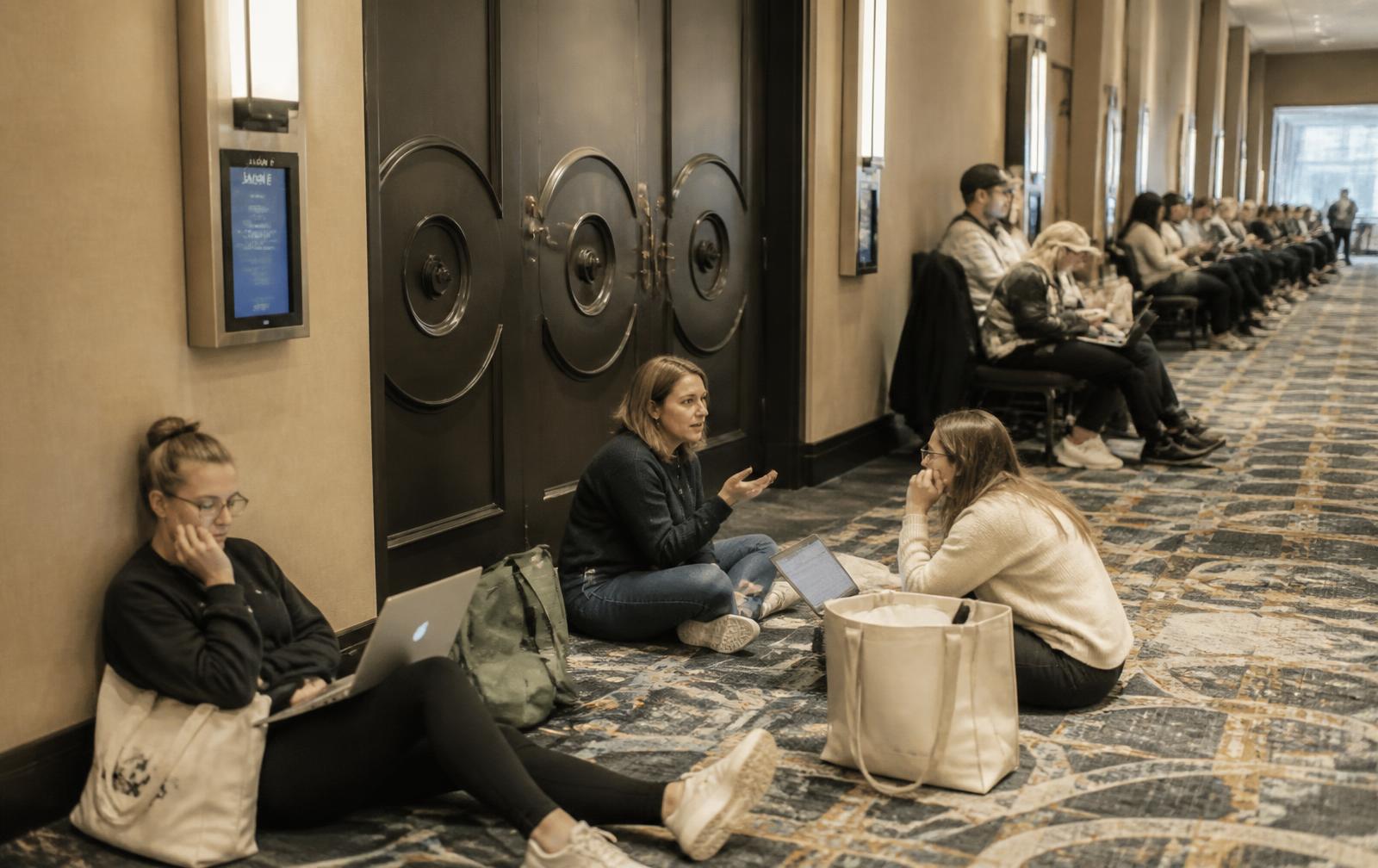 Parents working on laptops while seated along a hotel convention corridor